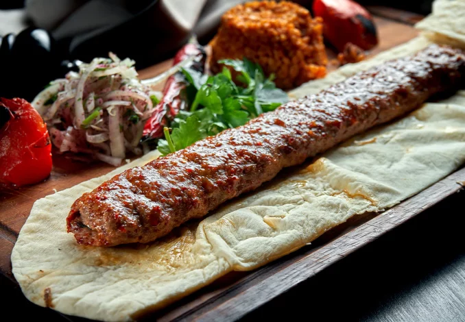 Delicious Adana Kebab recipe with grilled minced lamb, aromatic spices, and served with fresh vegetables